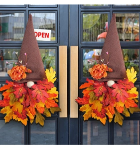 Pair of autumn gnome door hangers with maple leaves on a dark glass double door