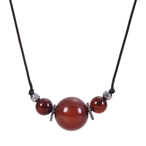Macro detail of natural red agate pendant with silver metal accents on black cord necklace