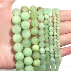 Natural light green Afghan jade round beads in various sizes held by a hand on white background