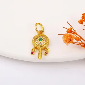 Macro view of gold-plated rattle-shaped pendant with green gemstone and red accents