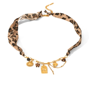 Detail of leopard print choker with golden sun, heart charms, and engraved metal pendant
