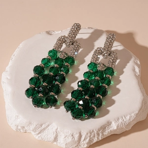Detail view of long tassel earrings featuring green crystal beads and sparkling rhinestones