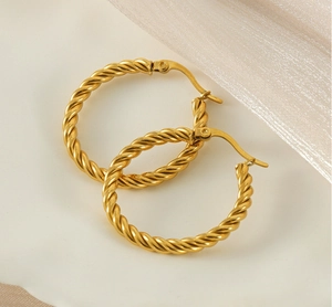 Détail macro des boucles d'oreilles créoles torsadées en acier inoxydable doré 18K