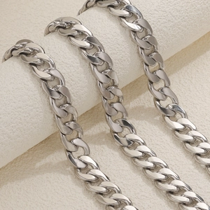 Polished silver stainless steel Cuban link chain necklace displayed on a textured stand