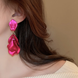 Macro view of tiered pink petal earrings with gold rings worn by a model in profile