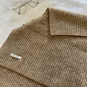 Flat lay of brown knit turtleneck shawl with ribbed texture and brand label