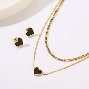 Detail of gold layered necklace with black heart pendants and matching stud earrings