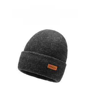 Detailed view of thick dark grey knit beanie with brown leather logo patch