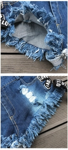 Dettaglio di pantaloncini di denim strappati con frange pesanti e nastro laterale