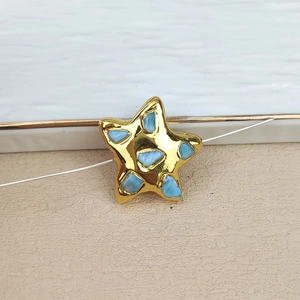 Close-up of gold plated star charm with blue gemstone inlay for DIY jewelry design