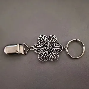 Détail d'un clip à pull rétro en métal argenté avec motif floral et pince crocodile robuste