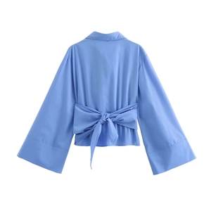 Détail d'une chemise en popeline bleu clair avec un nœud décoratif au dos et des boutons