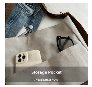 Detail view of canvas bag front pocket containing a smartphone and black-framed glasses