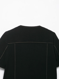 Detailed macro view of black fabric with orange contrast stitching and seam work