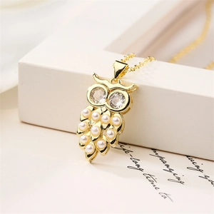 Macro shot of gold owl pendant necklace featuring white pearls and zircon eyes
