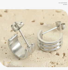 Vue macro détaillée de boucles d'oreilles argentées en C avec un design ondulé à trois couches