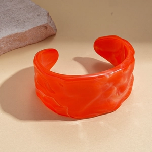 Macro detail of amber resin open bangle with marble texture and wavy edges