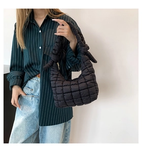 Detailed view of black quilted puffer bag featuring a knotted handle and puffy texture