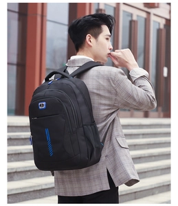 Man in grey suit wearing a black casual backpack featuring blue zippers and wide straps