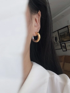 Detail of two-tone gold and silver chunky hoop earrings worn on ear with industrial style
