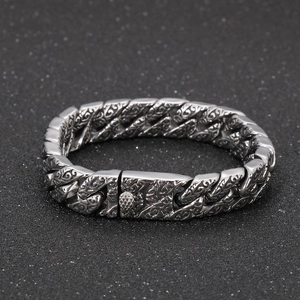 Detailed close-up of vintage engraved stainless steel link chain bracelet with floral motifs