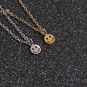 Dettaglio di pendenti con faccina sorridente in oro e argento su sfondo glitter nero