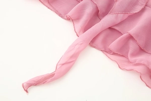 Gros plan sur le tissu mousseline rose léger avec des bords volantés délicats pour robe en V