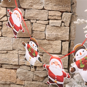 Detail of Christmas banner hanging on a stone wall with Santa and Snowman paper cutouts