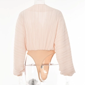 Back view of beige pleated long sleeve V-neck jumpsuit on clear mannequin with smooth fabric