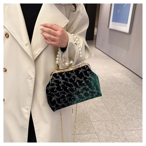 Detail of dark green velvet shell bag with pearl handle and elegant gold clasp