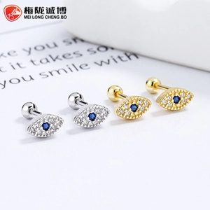 Macro detail of silver and gold evil eye stud earrings with blue zirconia stones