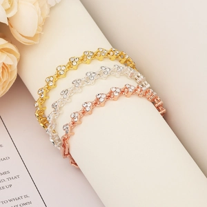 Close-up of elegant gold silver and rose gold zircon bracelets set against floral decor