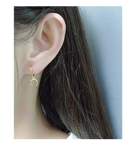 Macro view of a gold crescent moon earring worn on a model with elegant light luxury style