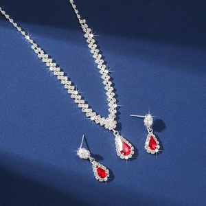 Detailed view of silver necklace and earrings set with red teardrop crystal pendants