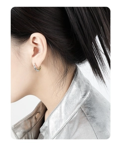 Detail of C-shaped geometric S925 silver earrings in two-tone gold and silver finish