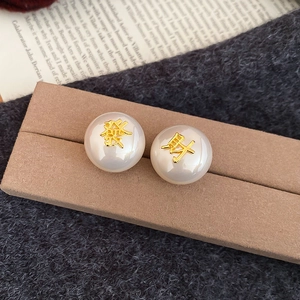 Vue détaillée de boucles d'oreilles en perles avec caractères porte-bonheur dorés