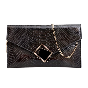 Clutch nera lucida con motivo a pietra, fibbia dorata geometrica e tracolla a catena