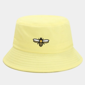 Close-up of a pale yellow cotton bucket hat featuring detailed bee embroidery on the front