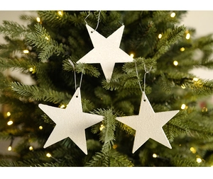 Three white glitter star ornaments hanging on a Christmas tree with warm lights
