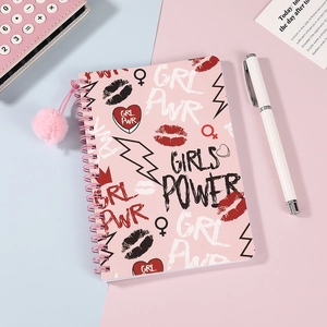 Detalle de cuaderno de espiral rosa con motivos Girl Power y colgante de peluche