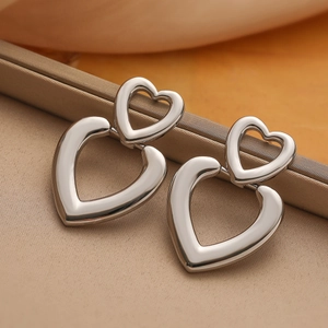Polished silver double heart hollow earrings on a champagne silk background