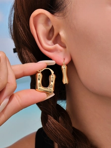 Detailed close-up of chunky gold U-shaped earrings with fluid geometric organic design