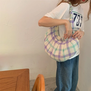 Detailed close-up of a purple and green plaid canvas shoulder bag with pleated handles