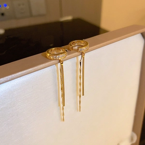 Close-up of gold-plated C-shaped ear cuff with sparkling zircon and long tassel chains