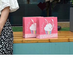 Pink paper gift bag with colorful cupcake prints and Happy Everyday text outdoors