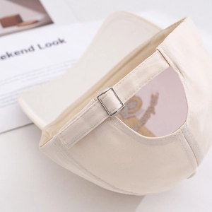Detail of beige cotton baseball cap featuring an adjustable metal buckle and stitching