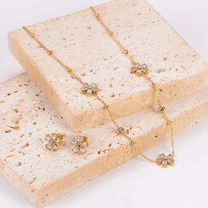 Elegant gold flower jewelry set with sparkling crystals displayed on natural stone