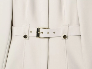Détail de la taille d'un blazer beige avec ceinture assortie et boucle métallique dorée