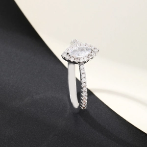Detailed view of marquise-cut white gemstone ring with halo pave setting on black background