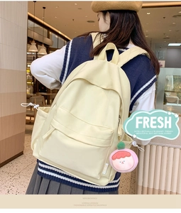 Detailed back view of a minimalist cream white backpack worn by a model in a shop